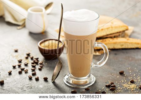 Hot coffee latte with brown sugar and biscotti cookies in tall glass