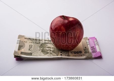 indian new currency notes of 500 and 200 rupees with fresh red apple and stethoscope - India and healthcare concept