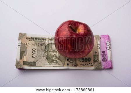 indian new currency notes of 500 and 200 rupees with fresh red apple and stethoscope - India and healthcare concept