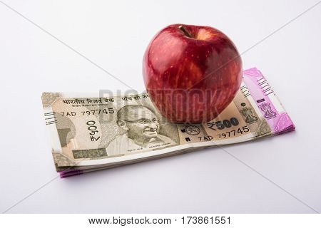 indian new currency notes of 500 and 200 rupees with fresh red apple and stethoscope - India and healthcare concept
