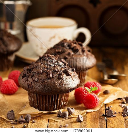 Double chocolate muffins with raspberry and a cup of coffee in a rustic setting