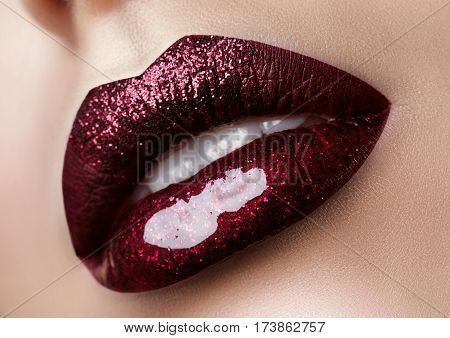 Close up view of beautiful woman lips with dark red lipstick. Fashion make up. Studio shot