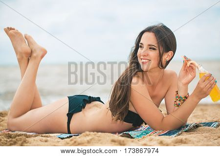 Beach woman drinking cold drink beverage having fun at beach party. Female babe in bikini enjoying orange water from glass boutle. summer concept