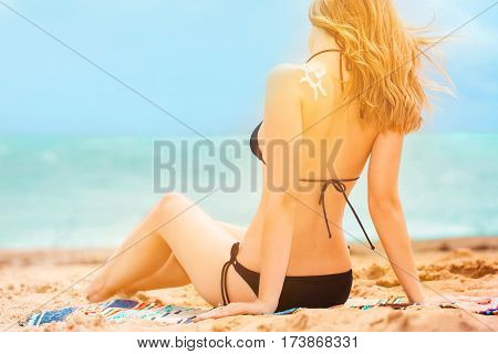 Young girl with suntan lotion having rest near seacoast. summer concept