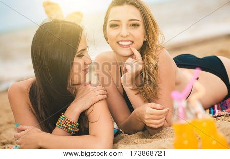 Gierlfriends drinking cold drink beverage having fun at beach party. Female babes in bikini enjoying orange water from glass boutle. summer concept