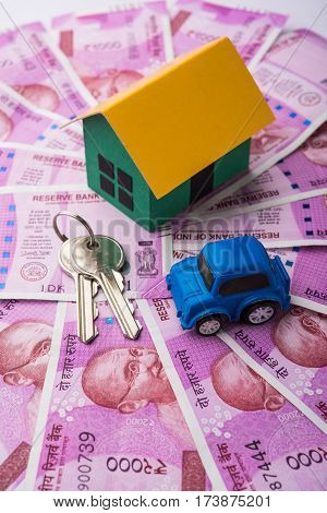 indian real estate or residential model house with new currency notes, keys, toy car and calculator, selective focus