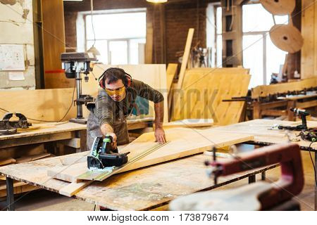 Woodworking artisan cutting wooden plank