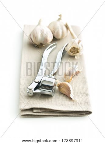 Garlic and garlic press on napkin isolated on white background.