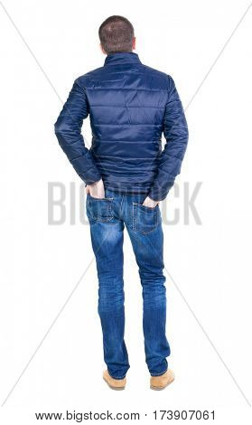 Back view of handsome man in blue windcheater looking. Standing young guy in jeans. Rear view people collection.  backside view of person.  Isolated over white background.