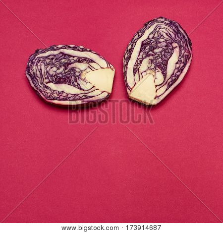 The fresh red cabbage cut in half on a red background