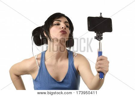 young attractive and sexy woman taking selfie photo with stick and mobile phone camera posing happy and playful sending kiss isolated on white background in shooting self portrait