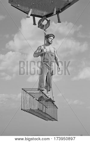 Higher heights. Black and white shot of a handsome muscular construction worker looking away standing on a crossbar at construction area professional handyman building developer confidence concept