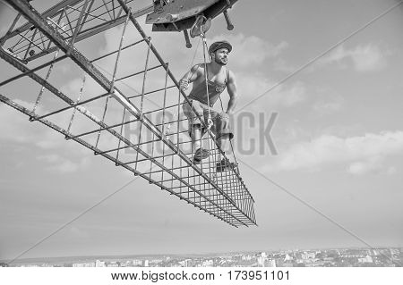 Professional handyman. Low angle black and white shot of a young muscular builder working at construction site looking away attentively working professionalism attention concentration people concept