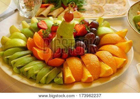 cut fruit creative designed plate on restaurant table close up photo
