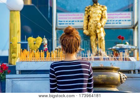 PATTAYA THAILAND - JANUARY 25: Girl praying at a traditional Thai Buddhist shrine with incense sticks in the background on January 25 2017 in Pattaya