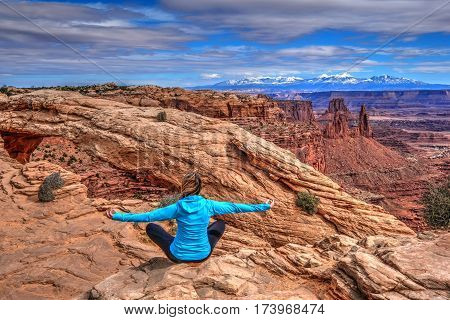 Young woman meditating at cliff by Mesa Arch. Canyonlands National Park. Moab. Utah. United States.