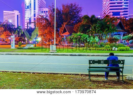 BANGKOK THAILAND - FEBRUARY 02: This is a night view Lumphini park with a man sitting on the bench and relaxing after jogging on February 02 2017 in Bangkok