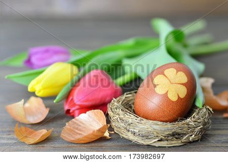 Happy Easter card: Easter egg in the nest and tulips