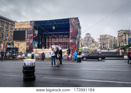 Two woman on a street in Kiev.
Kiev, Ukraine - May 15, 2014: Two woman on a street at Freedom square Kiev stopped to look in a camera, in the background, empty stage with signs and a few people around.
