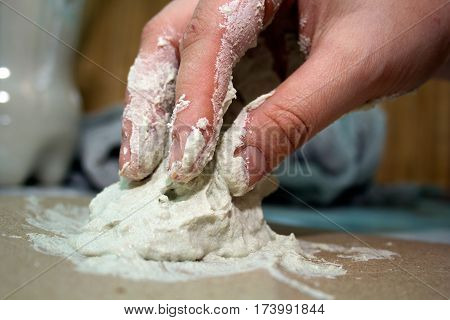 close up hands of ceramist with white clay