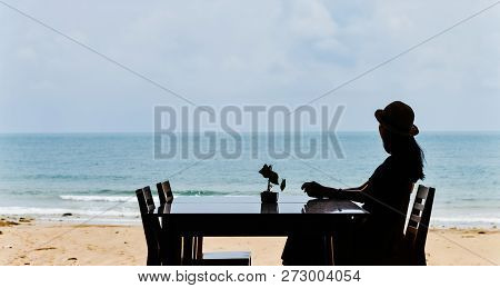 Single Asian Young Woman Sitting At Dining Table On Beach