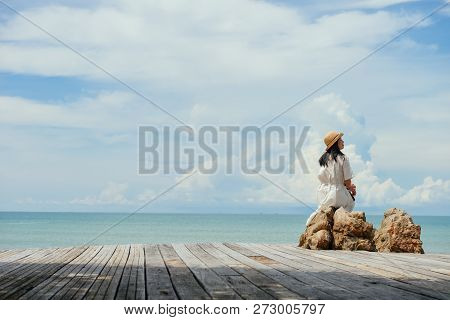 Single Asian Girl Looks Aside Sitting On Rock At Tropical Resort, Ao Nang, Krabi, Thailand.
