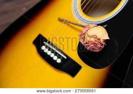 Acoustic Guitar With Dried Roses On The Wooden Table. Template For Advertising A Concert Of Memory S
