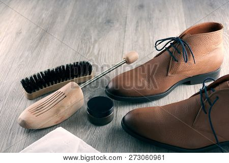 Brown Leather Desert Boots, Shoe Stretcher And Brush On A Wooden Floor
