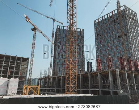 Under Construction High-rise Building With Yellow Construction Crane In The Sunlight.