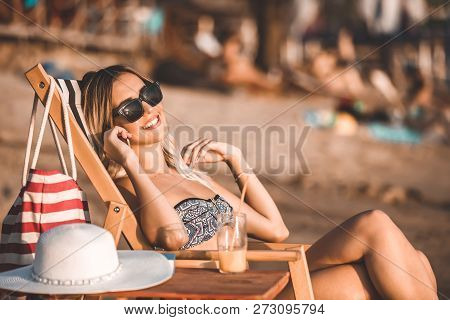 Happy Girl In A Swimsuit Talking On A Mobile Phone On The Beach