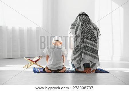 Muslim Man And His Son Praying Together Indoors