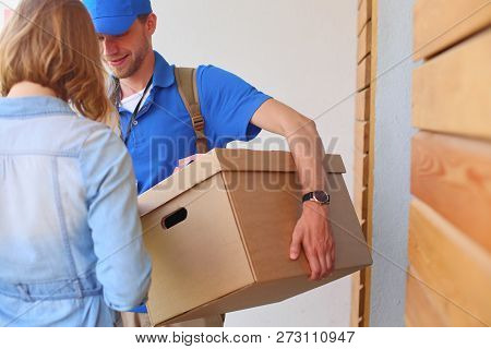 Smiling Delivery Man In Blue Uniform Delivering Parcel Box To Recipient - Courier Service Concept. S