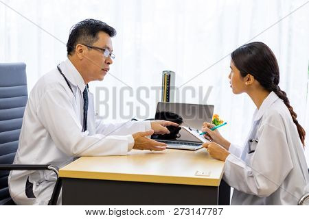 Two doctors in the hospital discuss the diagnos of the patient