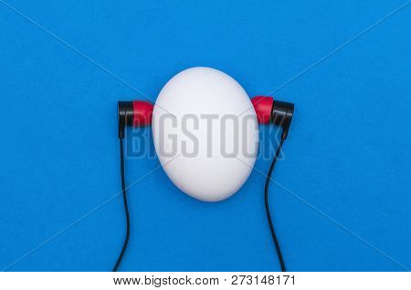 Chicken Egg Like A Man Head With Earphones Is Listening A Music Isolated On The Blue Background.