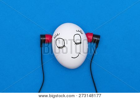 Funny Chicken Egg Like A Man Head With Earphones Is Listening A Music Isolated On The Blue Backgroun