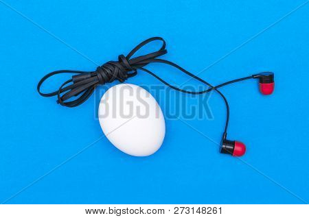 Chicken Egg And Headphones Isolated On Blue Background. Abtract Photo.