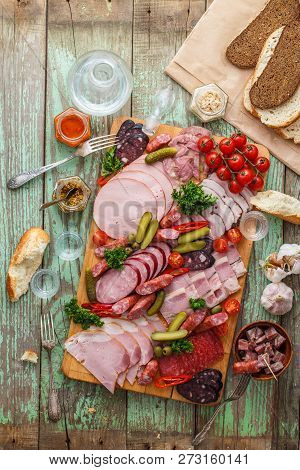 Assorted Sausages And Smoked Meat With Pickles, Bread And Vodka On Wooden Board, Top View Copy Space