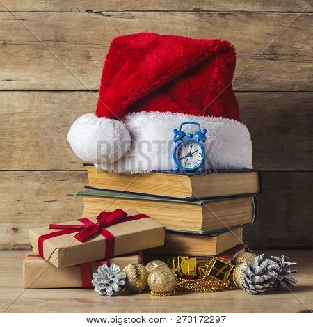 A Stack Of Books, Santa Clauss Cap, An Alarm Clock, Cones, Christmas-tree Decorations, Gift Boxes On
