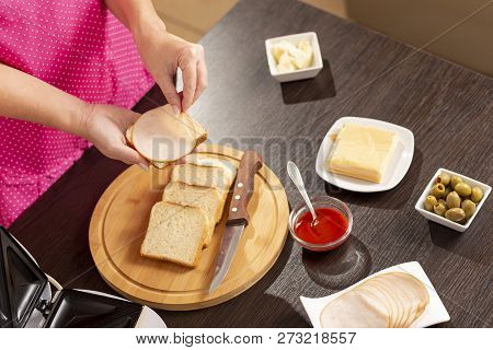 Detail Of Female Hands Adding Salami On A Sandwich; Woman Making Hot Sandwiches For Breakfast In A S