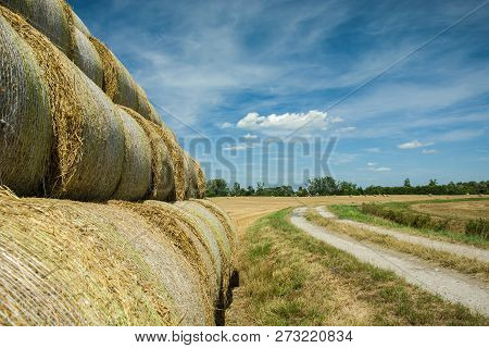 Stacked Hay Bales Along A Country Road, Horizon And Blue Sky