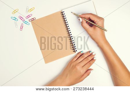 Female Hand With Pencil. White Sheet Of Paper On Desk. Notebook. Top View Of Work Desk. Mockup For Y