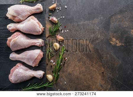 Chicken legs with spices and salt  ready for cooking on cutting board.