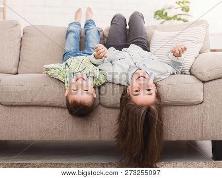 Go Crazy Together. Relaxing Upside Down On Beige Sofa At Home