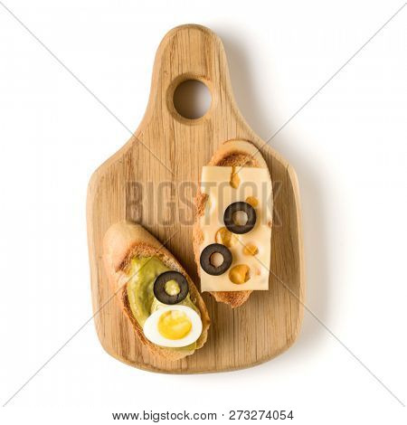 Open faced sandwich canape or crostini on a wooden serving board isolated on white background closeup. Top view.