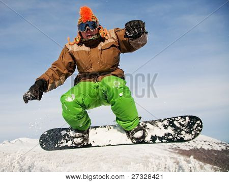 Snowboardista skoky vzduchem s tmavě modrou oblohou v pozadí