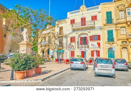 Naxxar, Malta - June 14, 2018: The Scenic Square With Historical Edifices With Bright Red Windows An