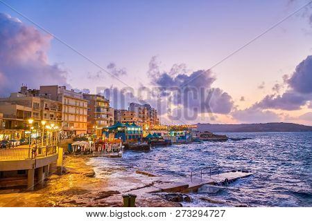 The View On The Coastline Restaurants  Bugibba Resort, And A Stormy Sea After Dusk, Malta