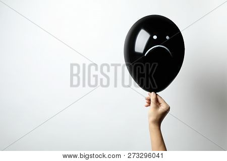 Woman Holding Balloon With Sad Face On White Background, Space For Text. Threat Of Depression