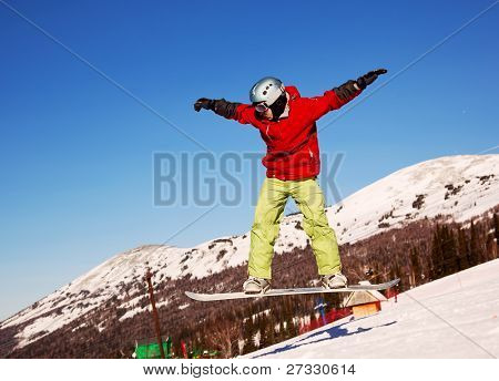 Snowboardista skoky vzduchem s tmavě modrou oblohou v pozadí