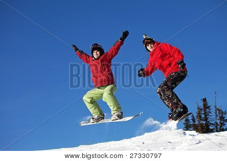 Snowboardista skoky vzduchem s tmavě modrou oblohou v pozadí